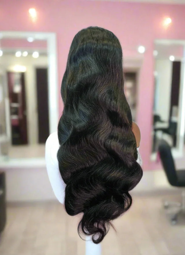 Long human hair wig with deep body waves displayed on mannequin in salon setting