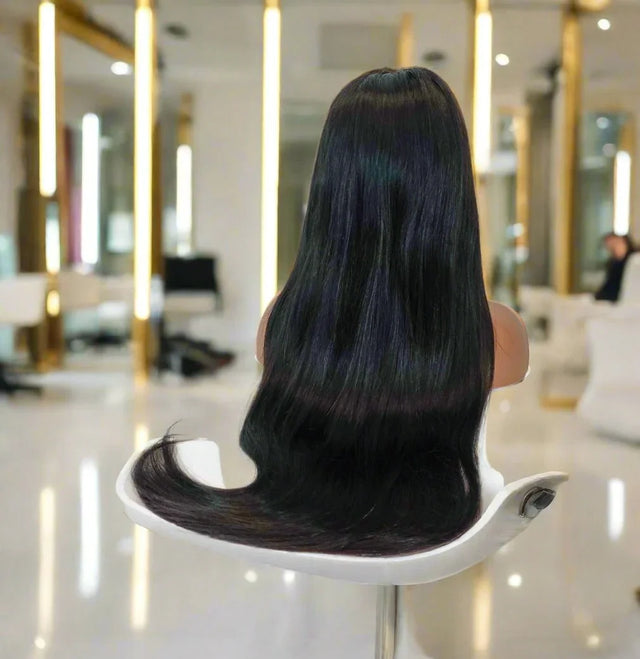 Long straight human hair wig on mannequin in salon, sleek black with subtle blue highlights