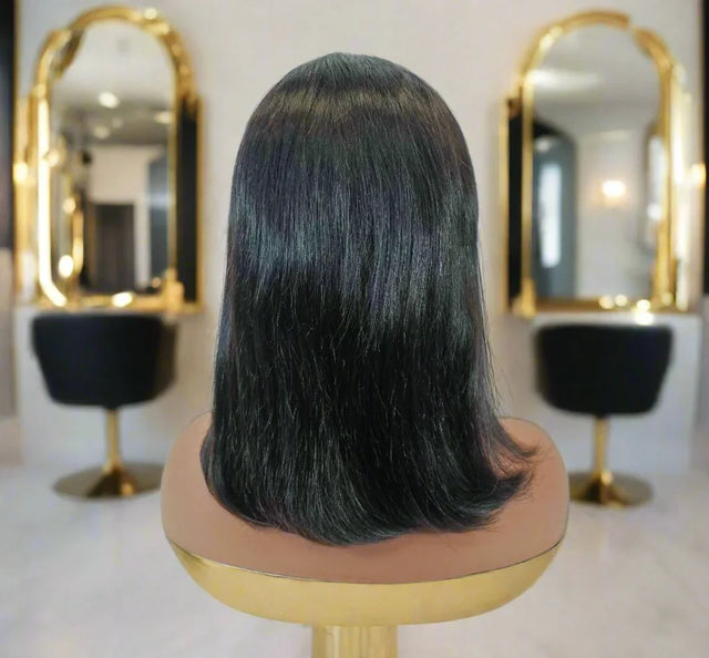 Smooth black human hair wig on mannequin, salon mirrors background, natural straight style