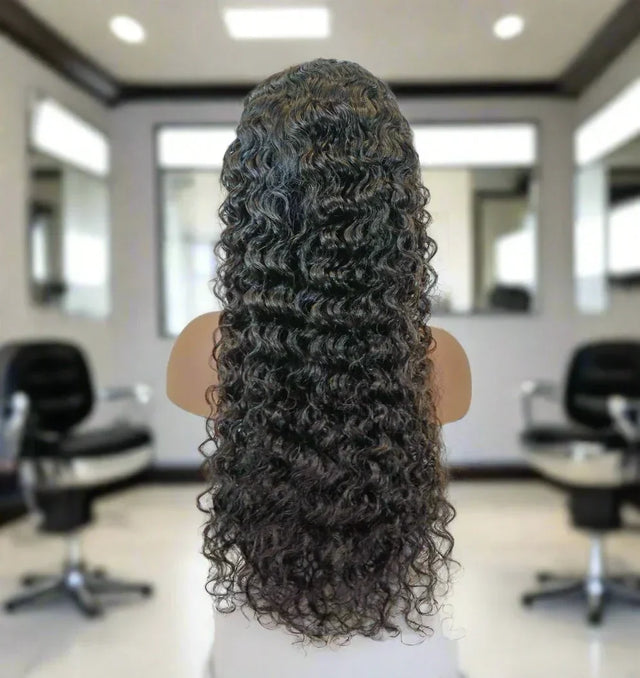 Long curly human hair wig displayed on mannequin in salon setting, natural voluminous curls