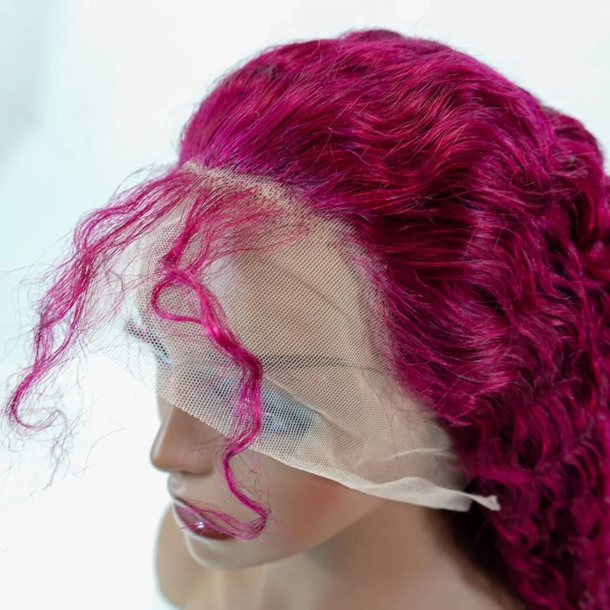 Vibrant magenta curly human hair lace front wig on mannequin, showcasing natural-looking hairline and volume.