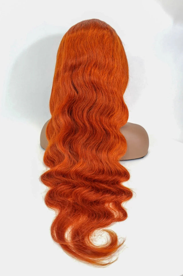Vibrant orange human hair wig with deep waves on mannequin head, natural styling ready