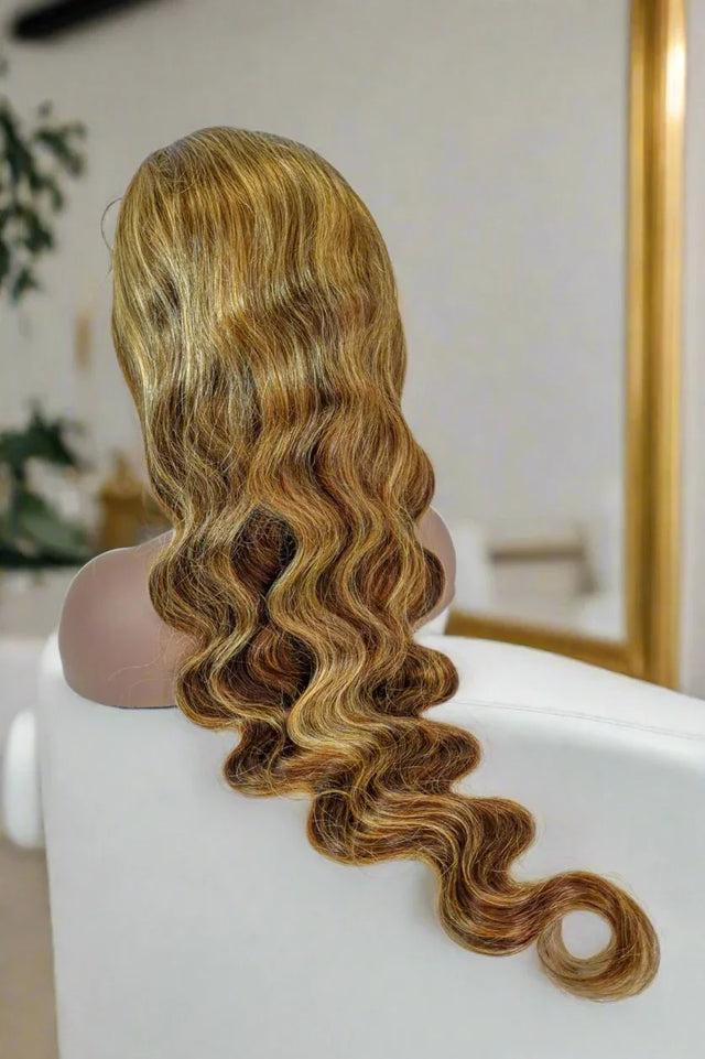 Long wavy human hair wig with honey blonde highlights on mannequin, natural styling ready