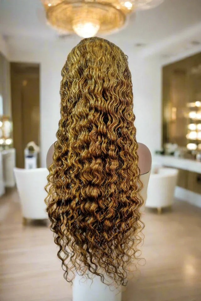 Long curly human hair wig with honey blonde highlights displayed on mannequin in salon setting