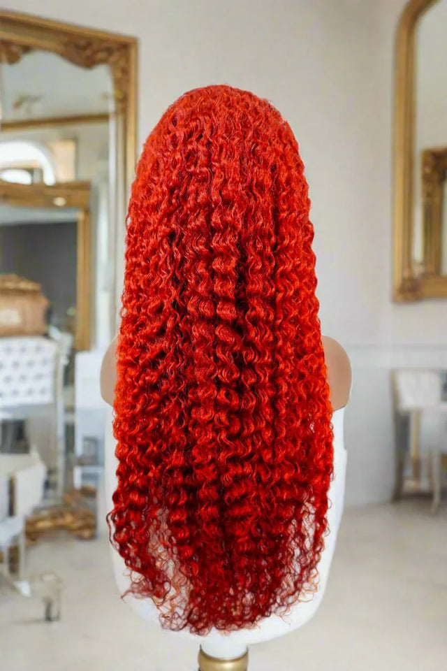 Vibrant red curly human hair wig on mannequin, luxury salon-style styling