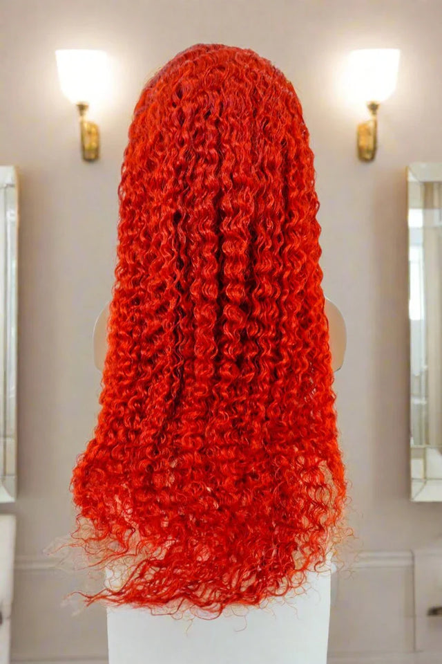Vibrant red curly human hair wig on mannequin, salon-style lighting