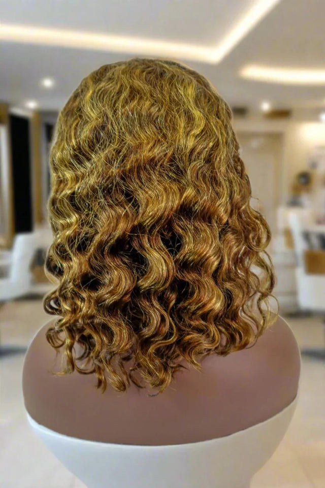 Curly human hair wig with golden highlights on mannequin, salon-style display
