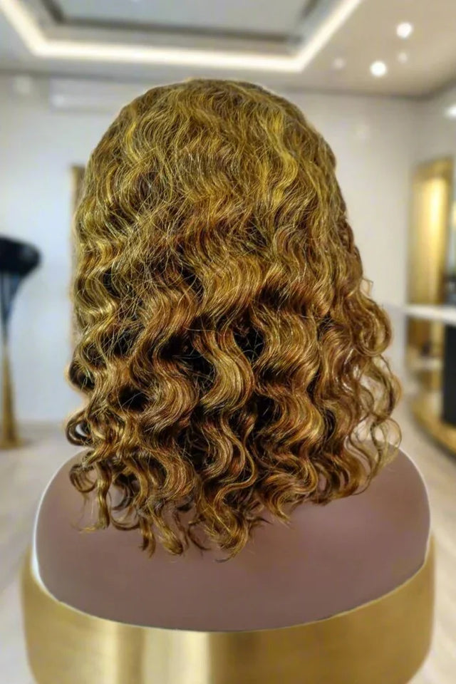 Curly human hair wig with honey blonde highlights on mannequin, salon-style display