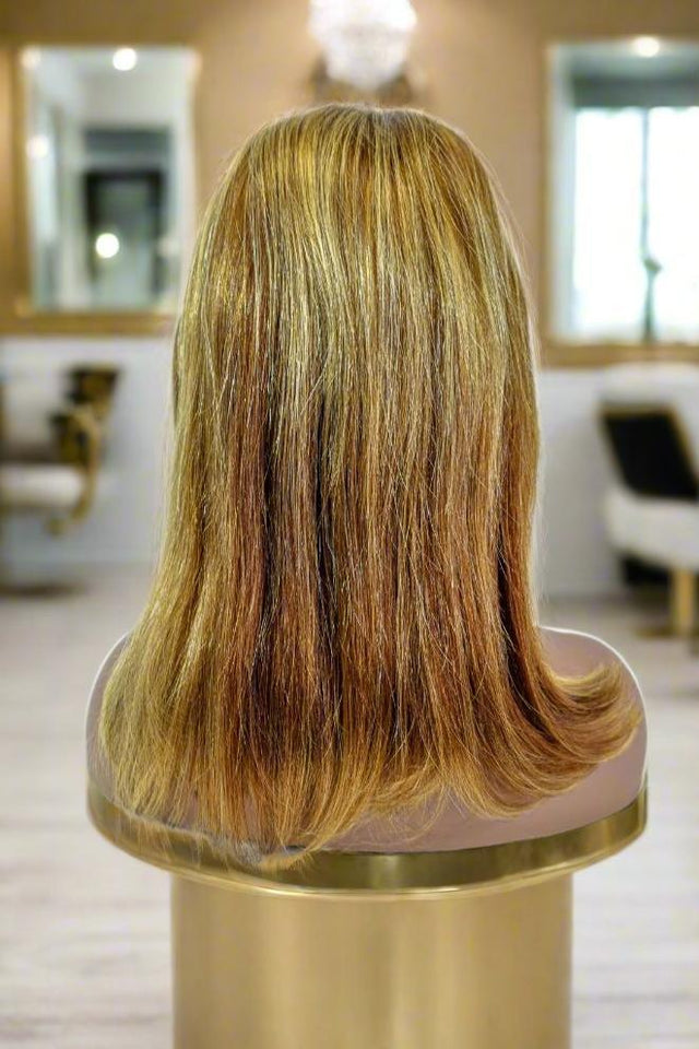 Long human hair wig with golden brown highlights displayed on mannequin in salon setting