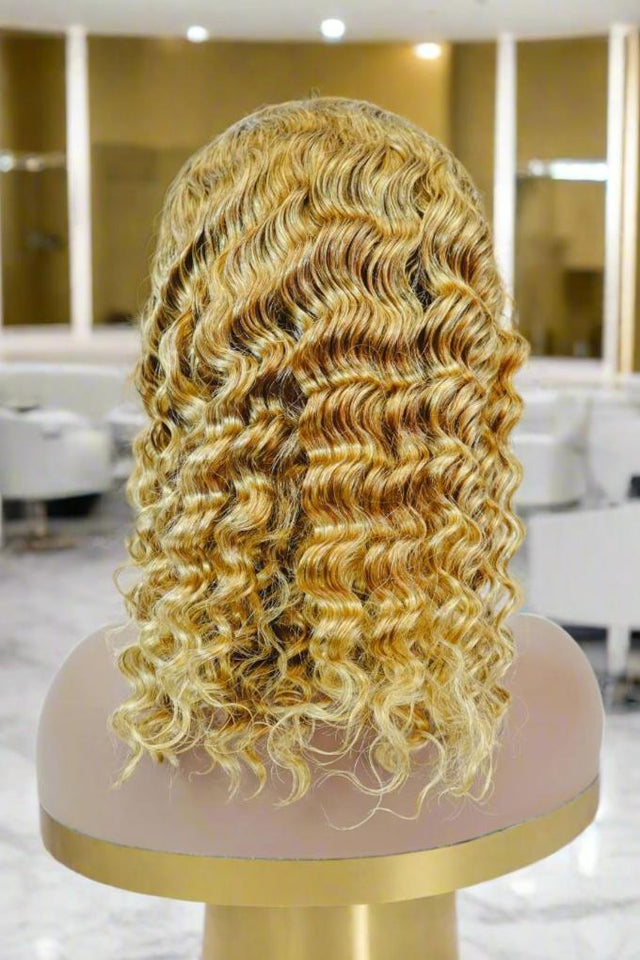 Blonde human hair wig with voluminous curls displayed on mannequin in salon setting