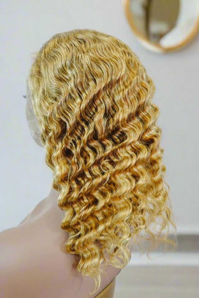Blonde human hair wig with voluminous curls, styled on mannequin for natural look