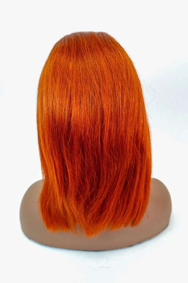 Vibrant orange human hair wig with sleek, straight cut displayed on mannequin head