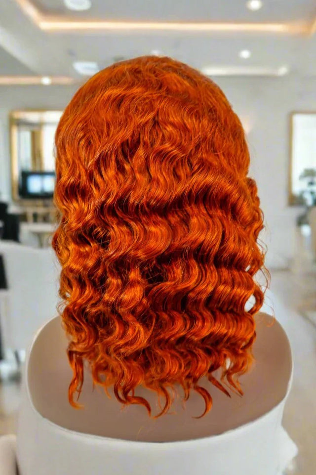 Vibrant orange curly human hair wig on mannequin, salon-style display