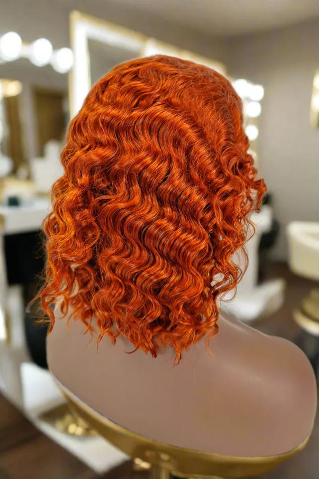 Vibrant red curly human hair wig on mannequin in salon setting, showcasing natural volume and texture