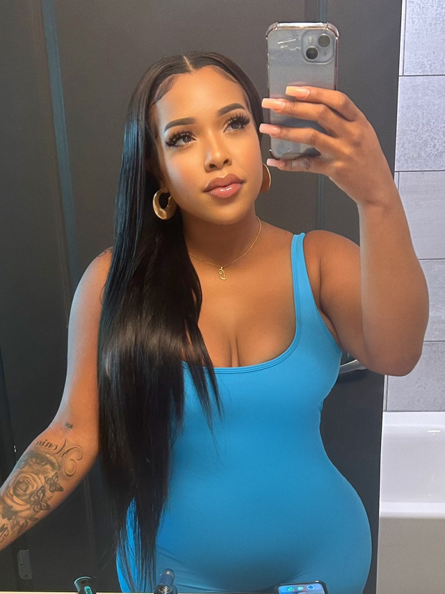 Woman taking mirror selfie with long straight human hair wig, blue top, gold hoops