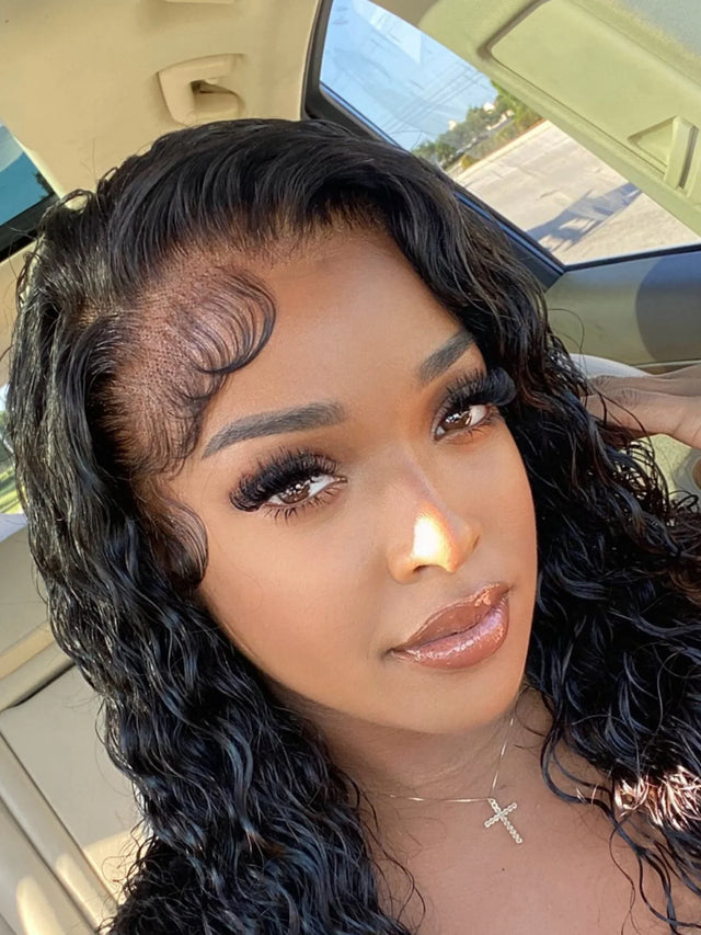 Woman wearing a natural-looking human hair wig with deep waves and lace front, styled in a car.