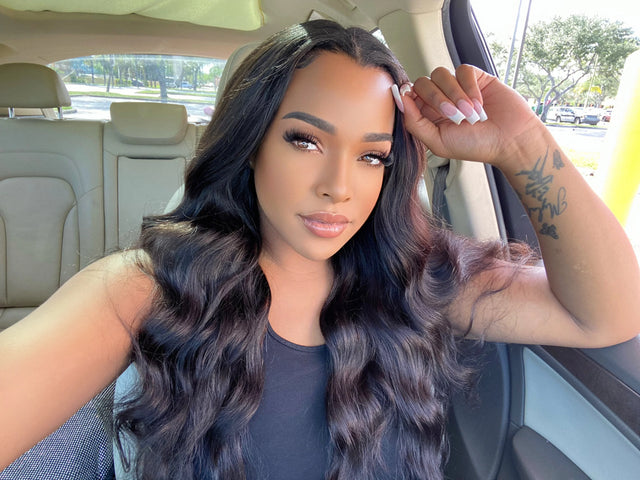 Woman with long wavy human hair wig, styled naturally in car, showcasing sleek texture and volume.