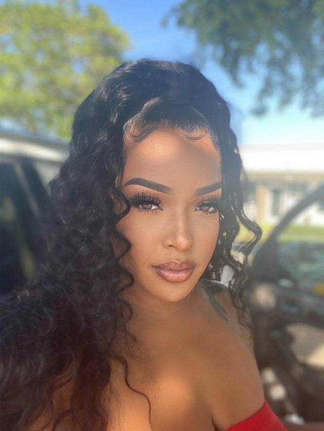 Woman wearing a natural-looking human hair wig with deep curls and lace front, styled outdoors.