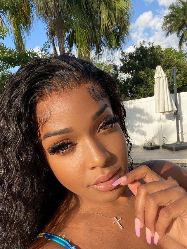 Woman with natural-looking human hair wig, wavy style, poolside under palm trees