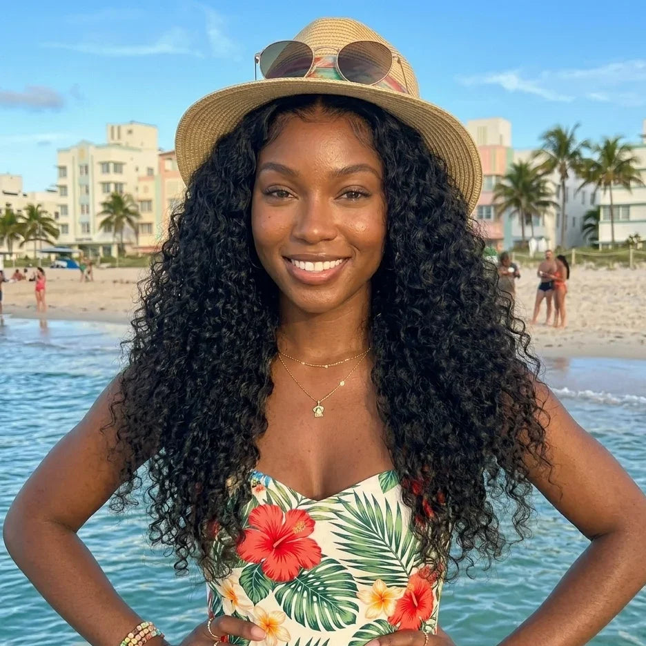 Woman with long curly human hair wig at beach, wearing floral top and straw hat