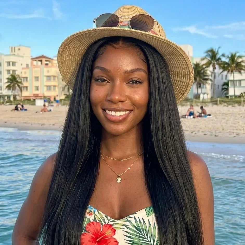 Woman with long straight human hair wig at beach, straw hat, floral top
