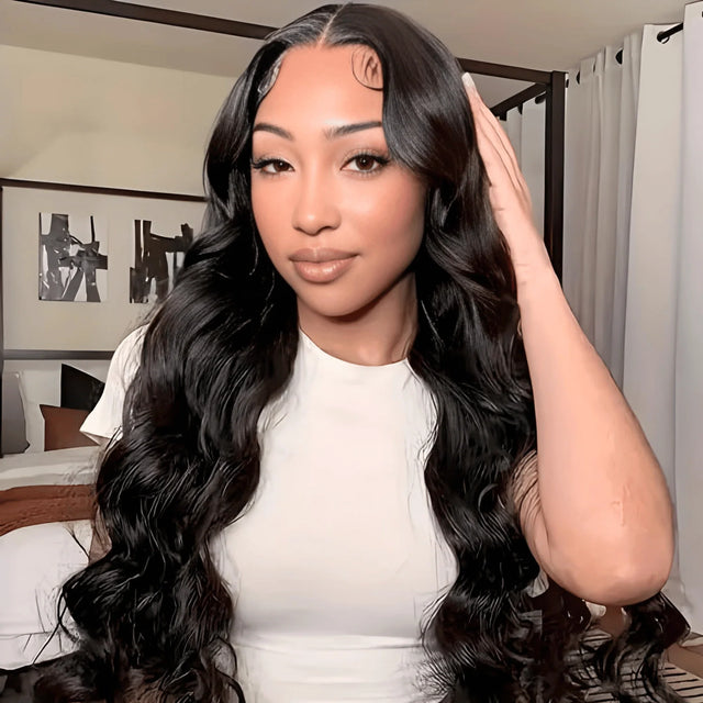 Woman wearing long, wavy human hair wig with natural-looking lace front, styled in bedroom setting