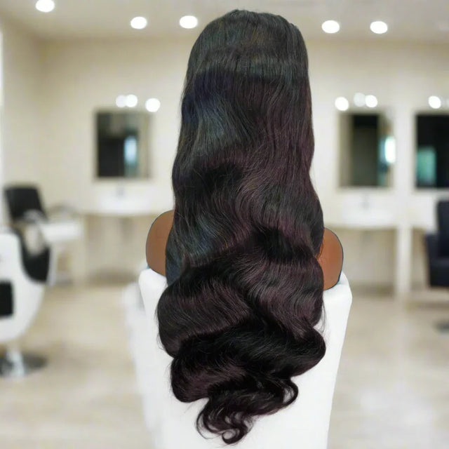 Long wavy human hair wig with dark roots and burgundy ombre, displayed on mannequin in salon setting