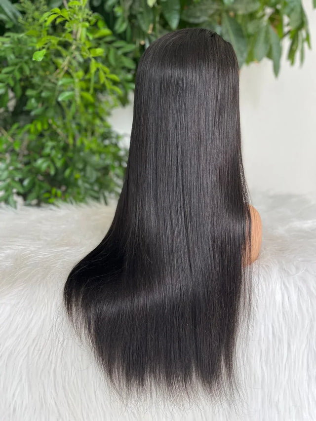 Long straight human hair wig on mannequin with lush green background, natural styling ready