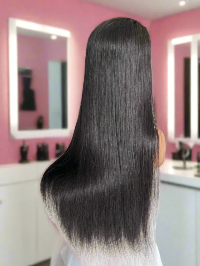 Long straight black human hair wig with ombre ends, shown from back in pink salon setting