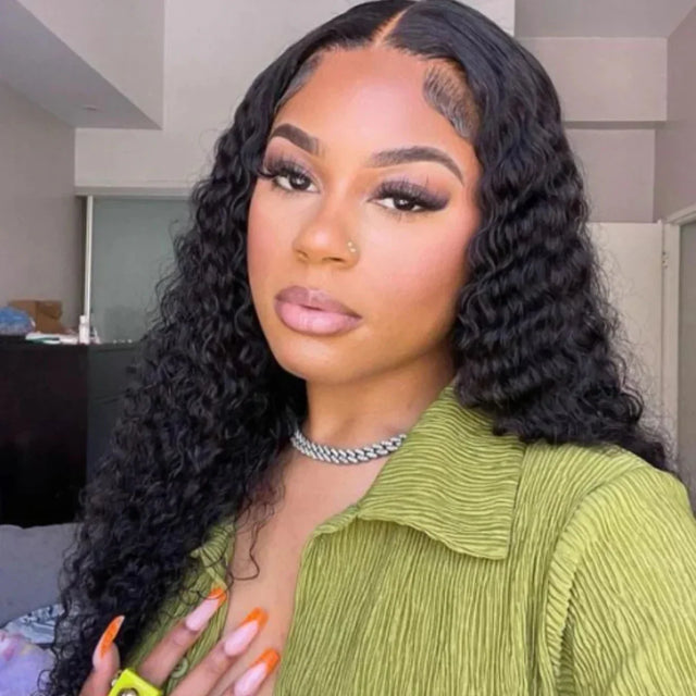 Woman wearing curly human hair wig with lace front, styled in loose waves, paired with green top and silver necklace