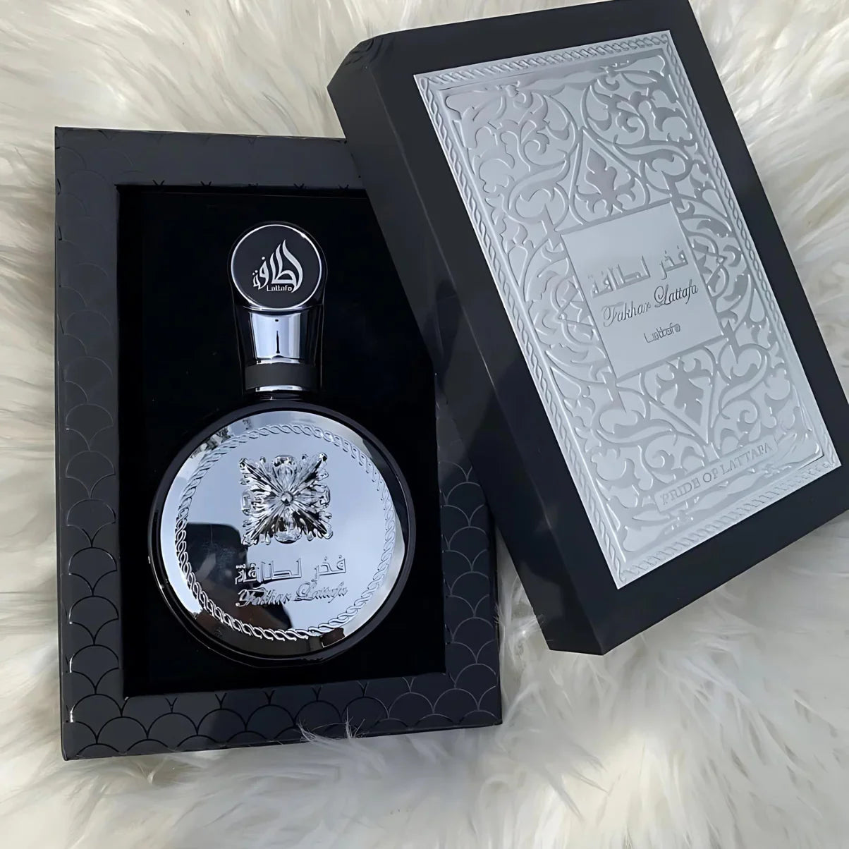 Luxury silver perfume bottle 'Fukhar Lattafa' in elegant black gift box on white fur