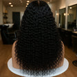 Long black curly human hair wig on mannequin in salon setting, natural waves and volume