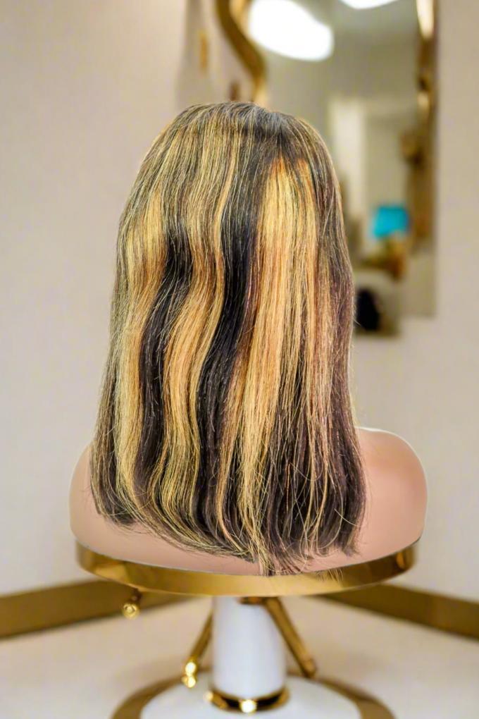Human hair wig with dark roots and blonde highlights, styled in loose waves on mannequin