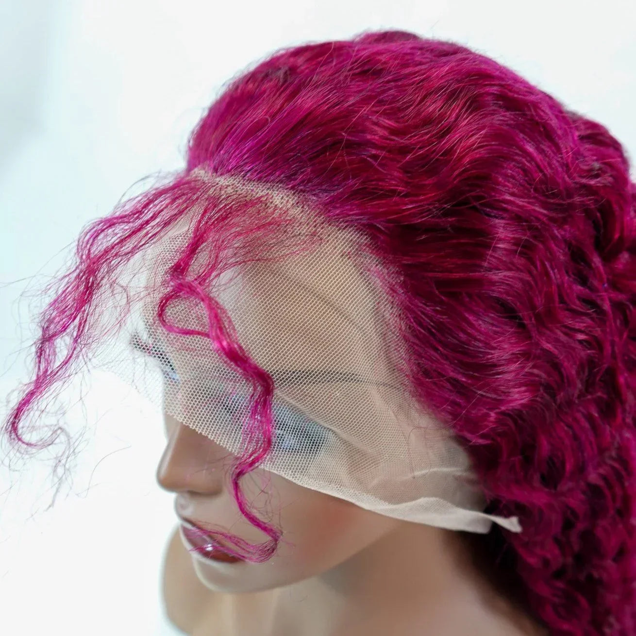 Vibrant magenta curly human hair lace front wig on mannequin, showcasing natural-looking hairline and volume.