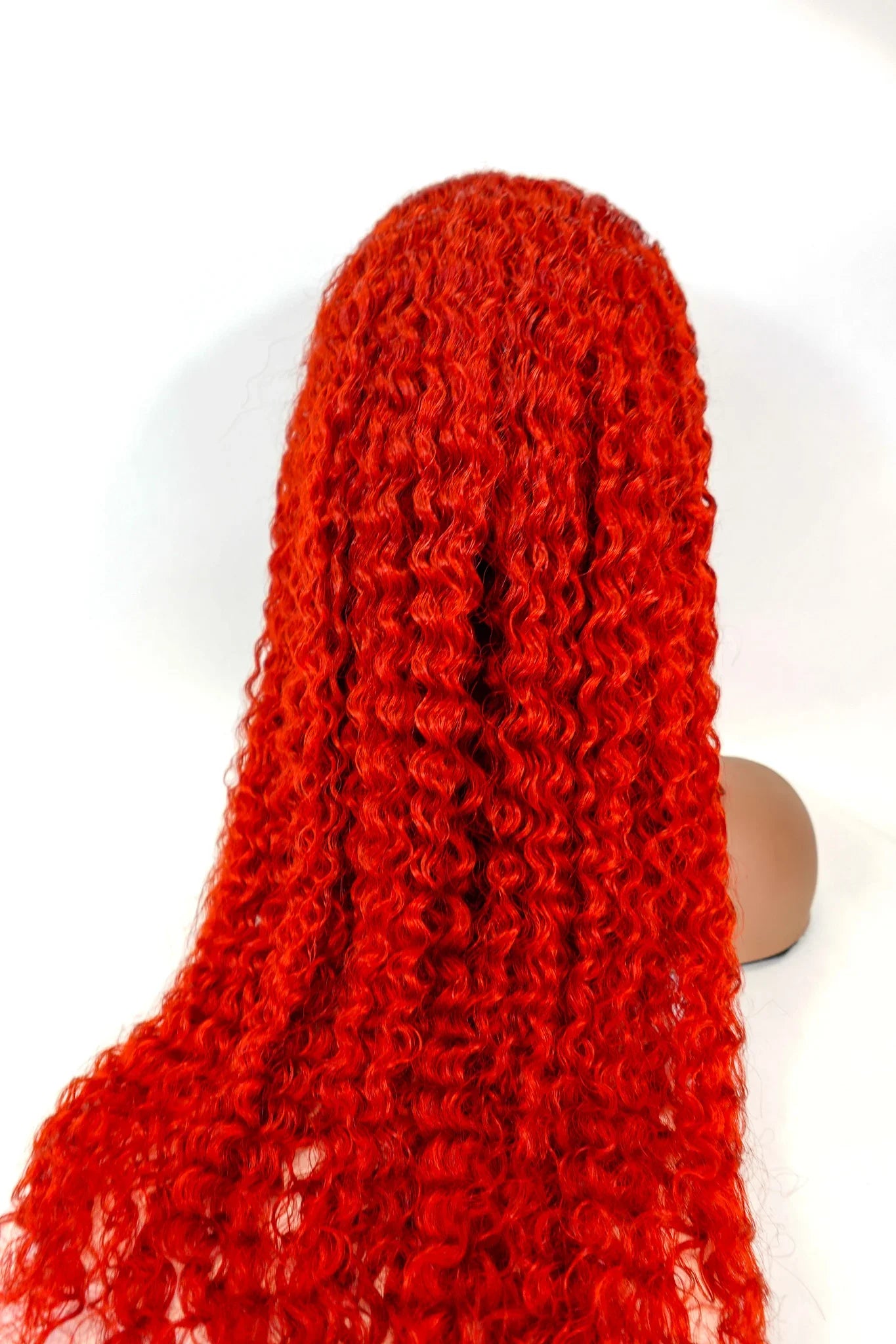 Vibrant red curly human hair wig on mannequin head, natural styling ready