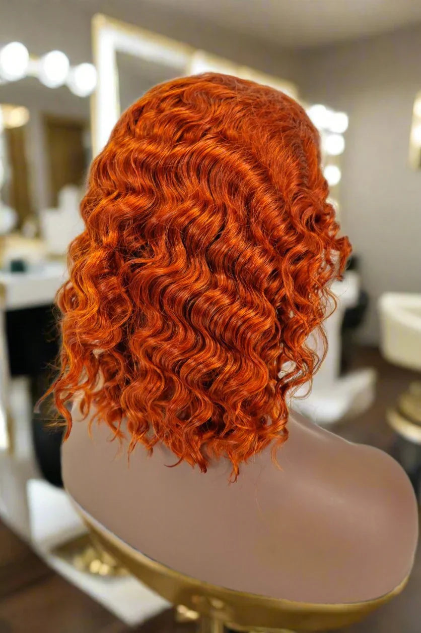 Vibrant red curly human hair wig on mannequin in salon setting, showcasing natural volume and texture