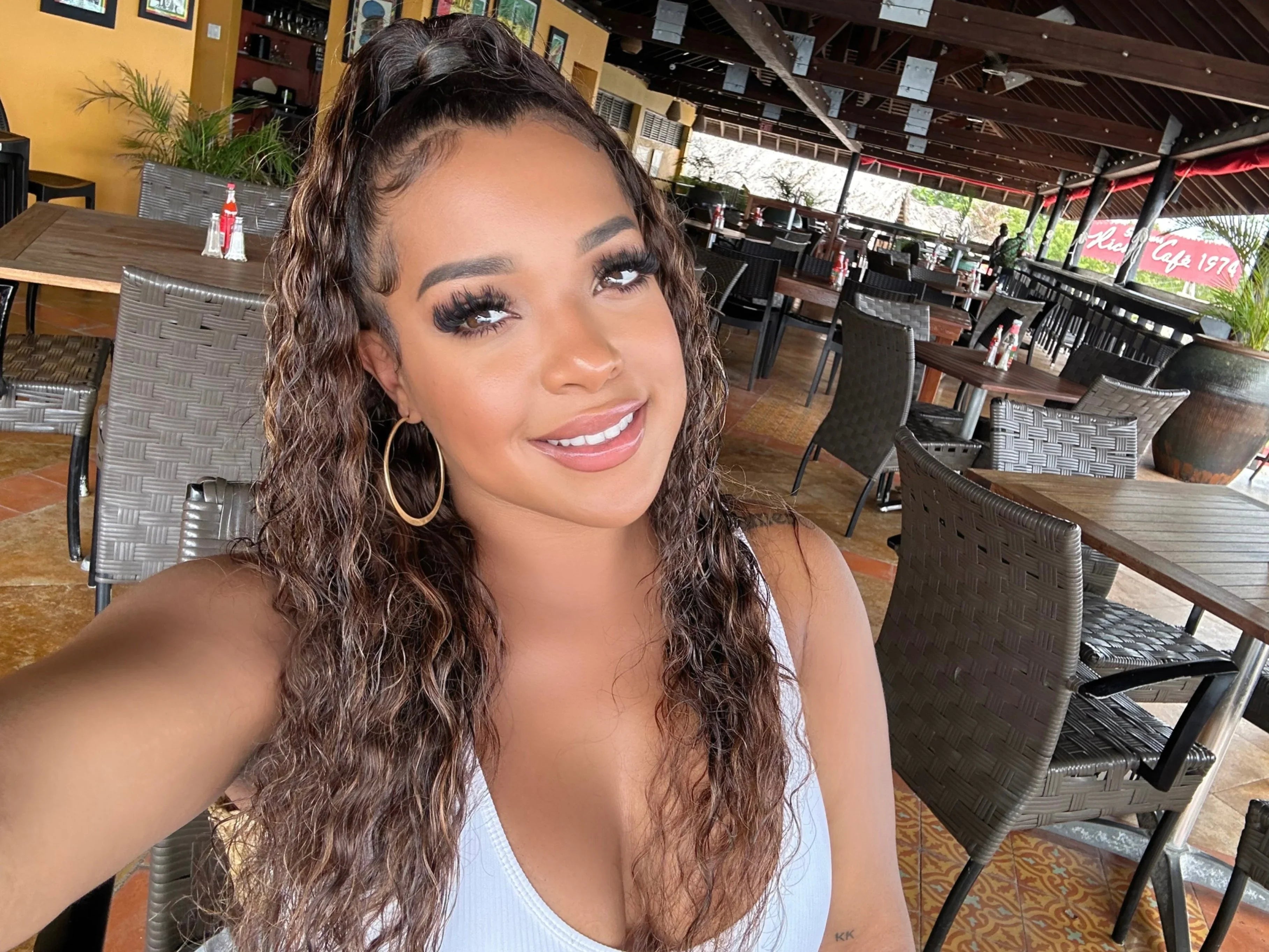 Woman with long curly human hair wig at outdoor cafe, natural styling
