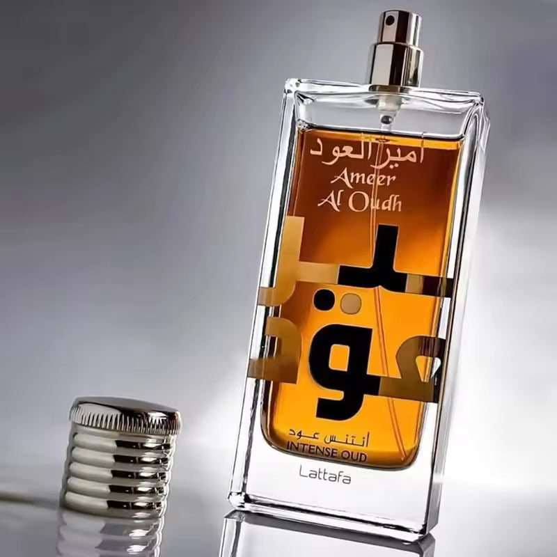 Ameer Al Oudh Intense Oud perfume bottle with Arabic script, amber liquid, and silver cap on reflective surface