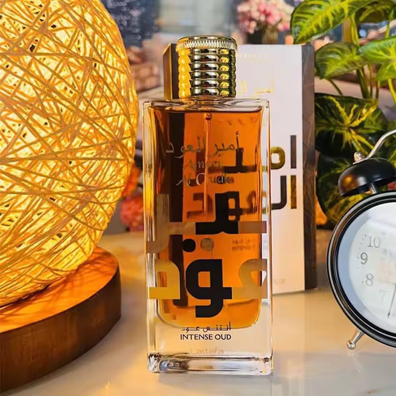 Luxury amber perfume bottle with Arabic text, gold cap, and warm lighting beside lamp and clock