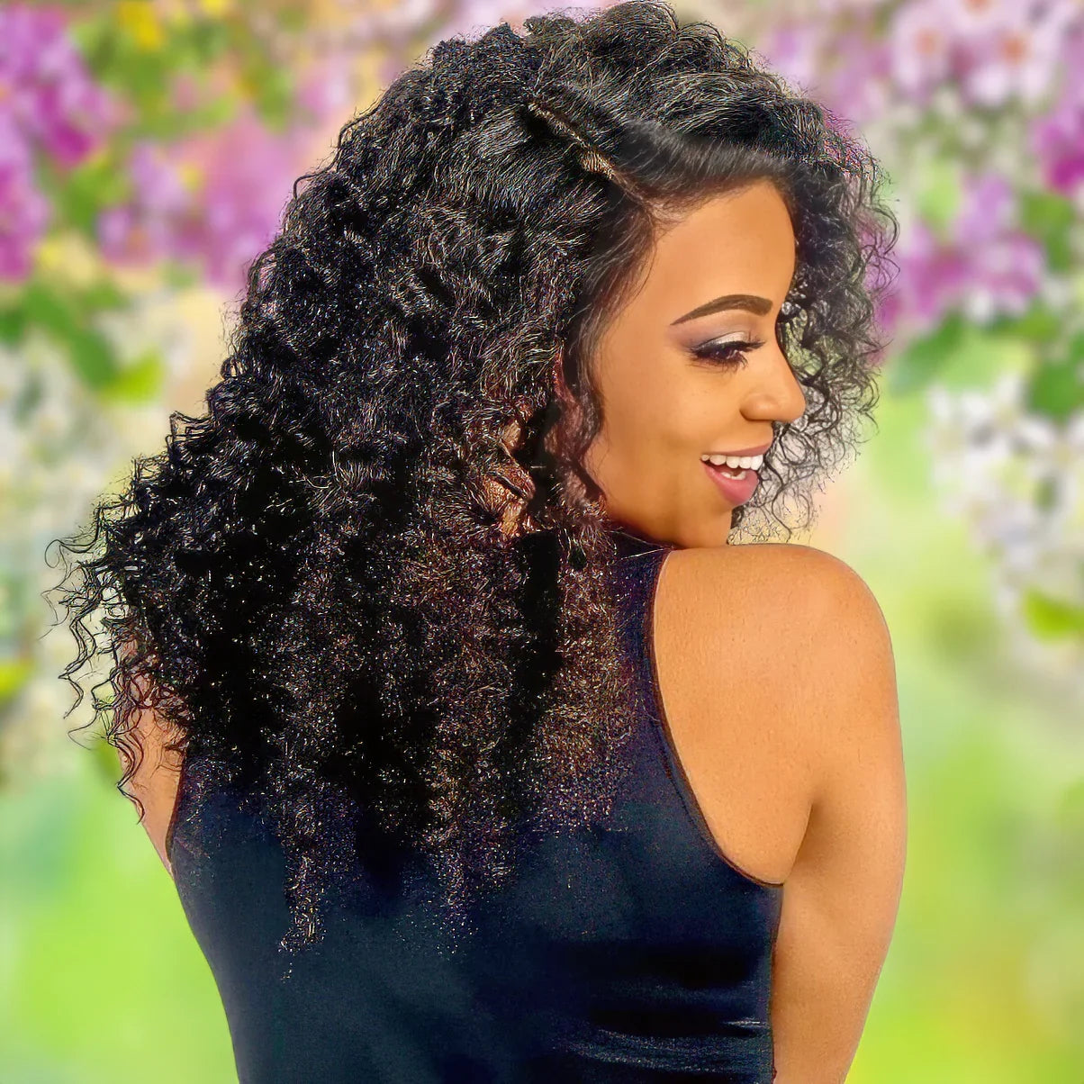 Woman with voluminous curly human hair wig, natural styling against floral backdrop