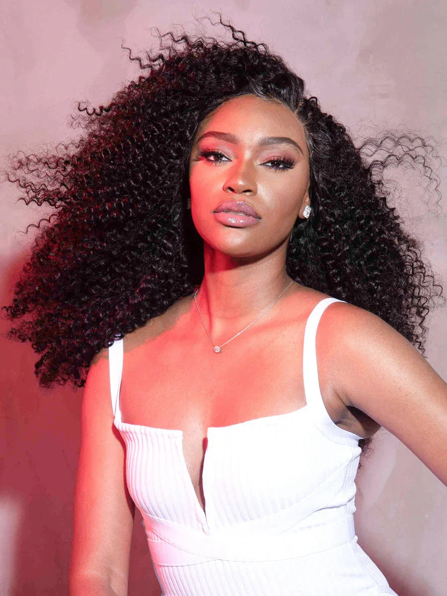 Woman wearing voluminous curly human hair wig, styled for natural look with white dress and soft lighting